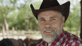 Portrait closeup of headshot handsome senior cattle farmer with gray beard wearing cowboy hat standing smiling and looking at camera with happiness in the countryside at an animal livestock cow farm.  - Powered by Shutterstock - Get 15% off with code: PIKWIZARD15