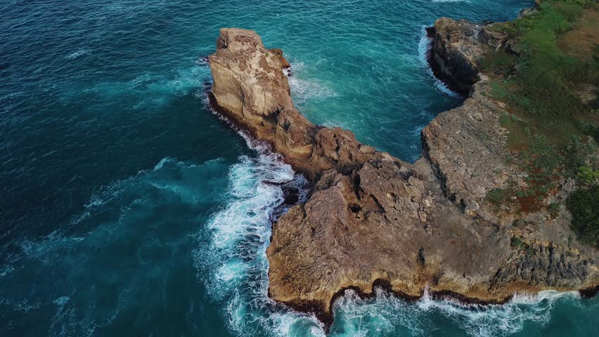 Aerial view of the wild tropical coast of the Dominican Republic with rocky cliff and untouched nature.A light breeze rolls onto shore with turquoise ocean waves.A luxurious landscape for relaxation