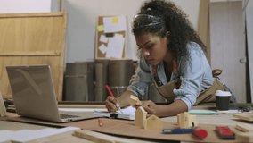Happy young black female carpenter worker standing in a workshop using a laptop computer for design and creativity model woodwork with sketch drawing on paper at workplace in the furniture factory.  - Powered by Shutterstock - Get 15% off with code: PIKWIZARD15