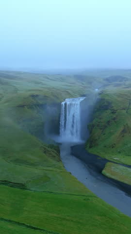 Dive into the breathtaking beauty of Iceland, Icelandic waterfall Skogafoss mesmerizing aerial footage of majestic waterfall amidst serene green landscapes, showcasing tranquility and natural allure
