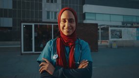 Young female doctor wearing blue uniform and red hijab during a break outside the hospital. - Powered by Shutterstock - Get 15% off with code: PIKWIZARD15