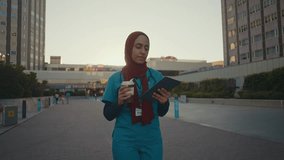 Young female doctor wearing blue uniform and red hijab during a break outside the hospital. - Powered by Shutterstock - Get 15% off with code: PIKWIZARD15