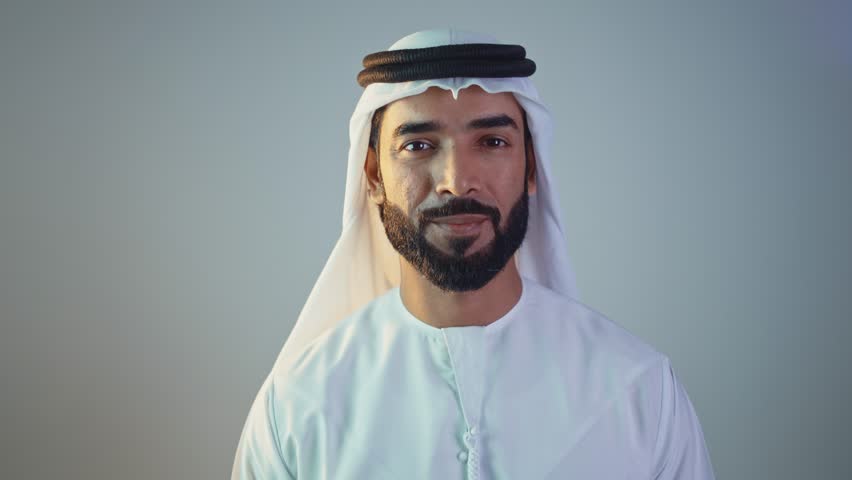 Handsome saudi arabian middle-eastern man with traditional thwab portrait in studio on colored backgrounds and gel colored lights.	
