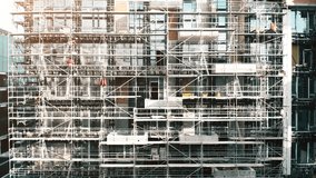 Construction workers installing scaffolding on a modern building in a busy urban area during daylight hours - Powered by Shutterstock - Get 15% off with code: PIKWIZARD15