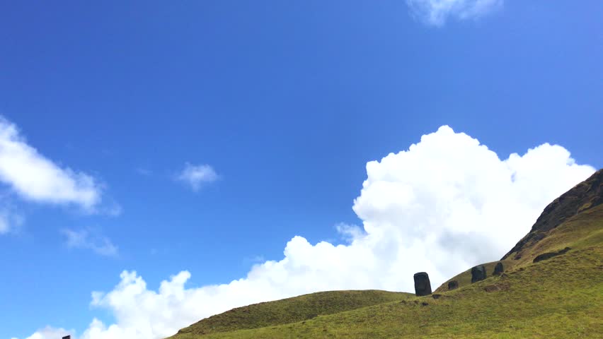 A group of beautiful moais in a sunny landscape over Ranu a Raraku in a summer day in Easter Island, Rapa Nui, Polynesia, Chile, Latin America.
