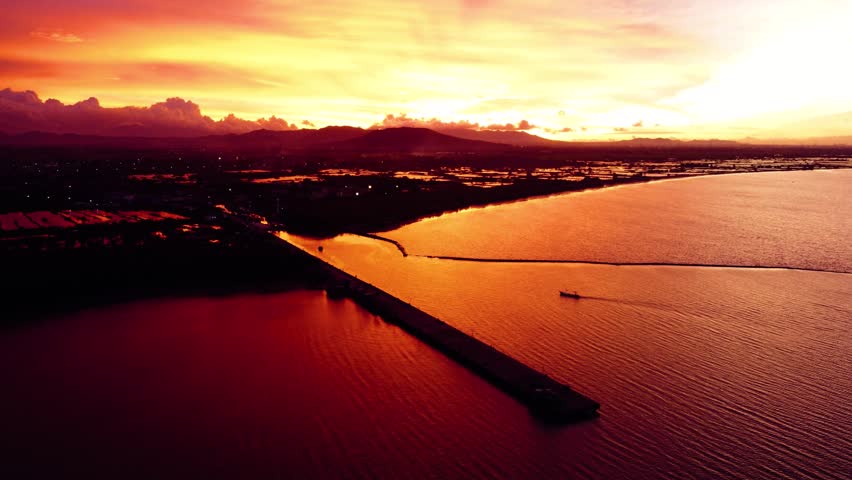 A stunning sunset in Indonesia paints the sky in vibrant oranges and reds. People gather, savoring the breathtaking view and the tranquility it brings.