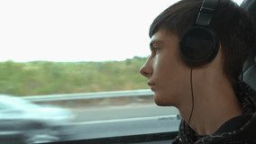 Sad thoughtful boy in headphones sits in bus, gazing out window with pensive expression. Teenager capturing quiet moment of introspection and daydreaming. Puberty, solo travel, vacations alone - Powered by Shutterstock - Get 15% off with code: PIKWIZARD15