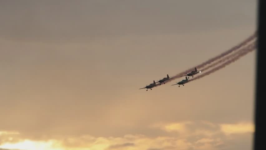 Squadron of four silhouetted propeller airplanes flying in formation in front of sunset or sunrise in super slow motion