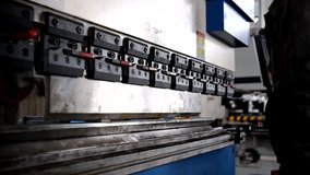 Man working with sheet metal on CNC hydraulic press brake. He puts the part and bends it into a large machine at an angle - Powered by Shutterstock - Get 15% off with code: PIKWIZARD15