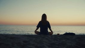 Yoga practice at sunset on a sandy beach by the sea. A woman practices asanas with the calm sea as her backdrop, bathed in the warm glow of sunset. A serene and peaceful scene, ideal for wellness cont - Powered by Shutterstock - Get 15% off with code: PIKWIZARD15