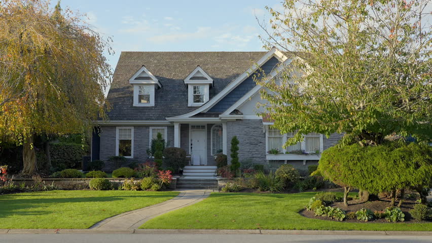 Establishing shot. Two story stucco luxury house with garage door, big tree and nice Fall Foliage landscape in Vancouver, Canada, North America. Day time on Sept 2024. ProRes 422 HQ.