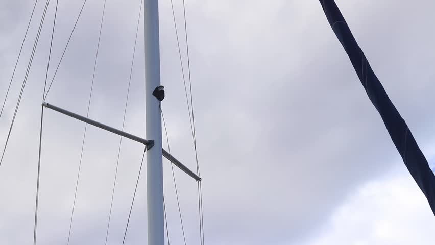 Furled sail against the sky. Furling sail on a sailing yacht. Close-up of a small yacht's sail. Boats with masts. Blue sail furled on a sailboat's stay