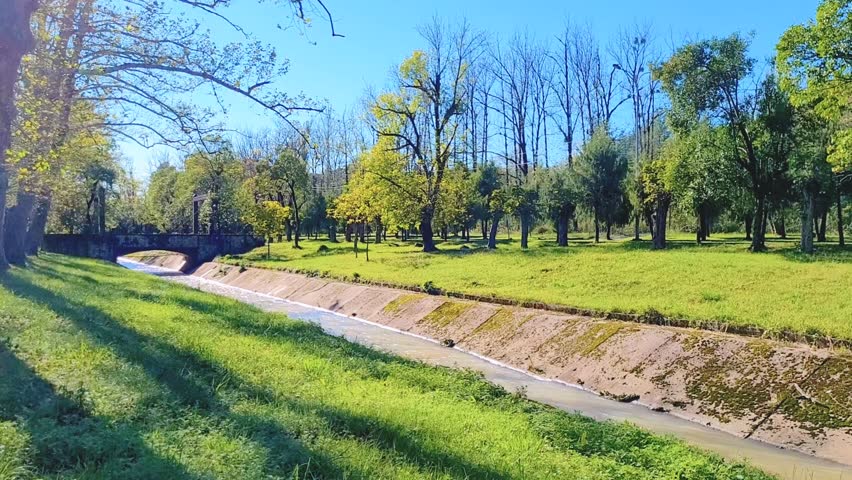 park and river - autumn park, frozen nature, green grass, river bed in concrete banks, large solid bridge