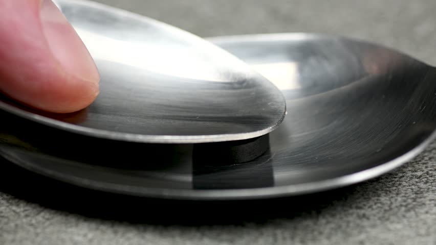 Black pill being crushed under a spoon on black background, health care medicine concept, macro, close up