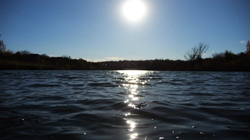 View on lake with waves at sunny summer day. Calm scenery of pond with sunlight at background. Beautiful nature landscape. Concept of tranquility scene. Slow motion