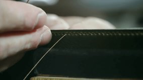 Close-up view showcases a shoemaker's hands skillfully stitching green leather using a needle and thread, highlighting the precision and craftsmanship involved in leatherwork - Powered by Shutterstock - Get 15% off with code: PIKWIZARD15