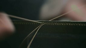 Close-up view showcases a shoemaker's hands skillfully stitching green leather using a needle and thread, highlighting the precision and craftsmanship involved in leatherwork - Powered by Shutterstock - Get 15% off with code: PIKWIZARD15