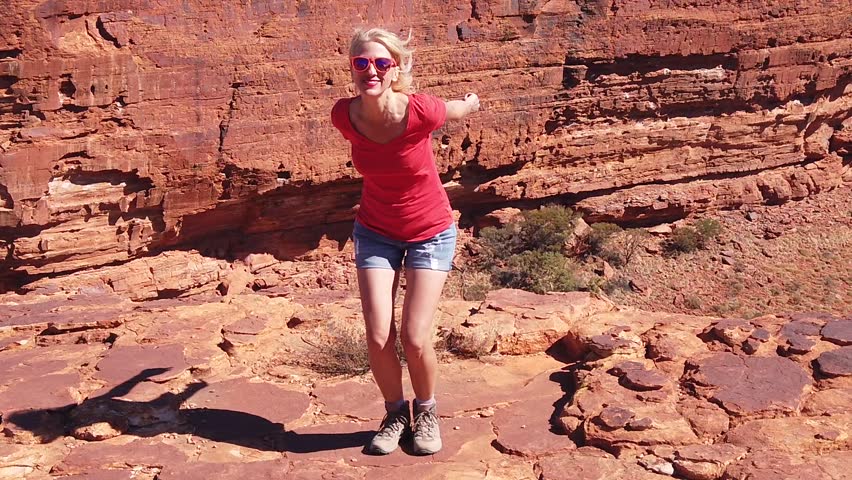 SLOW MOTION: Travel freedom concept. Hiking girl jumping at Kings Canyon in Red Center Outback. Jumper among sandstone formations in Watarrka National Park. Northern Territory, Central Australia.
