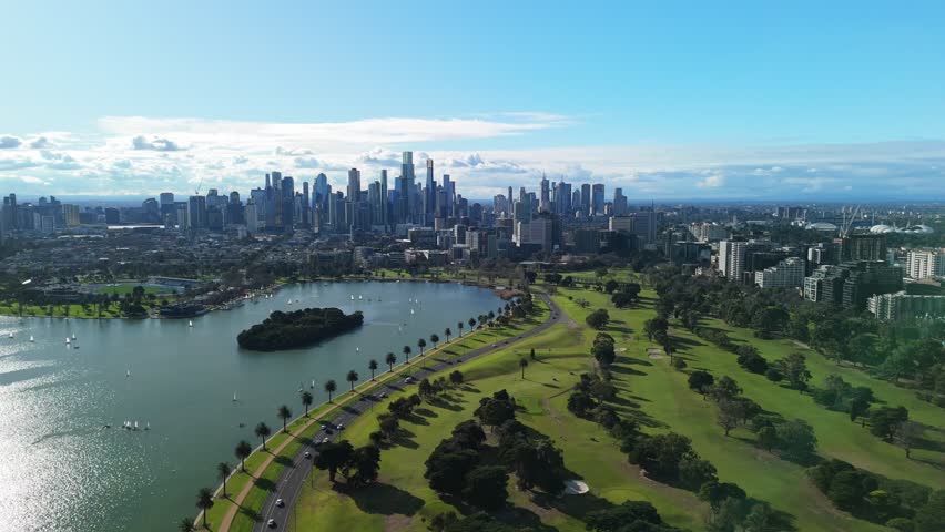 Scenic aerial flight over Albert Park lake in Melbourne on clear summers day with sailing boats racing.