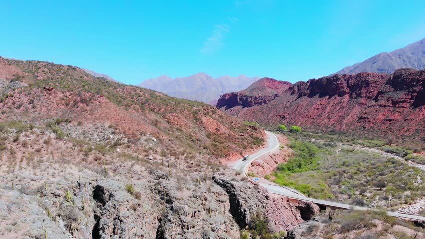 Bus on a road with colorful mountain peaks in the andes mountains, Cuesta de Miranda, La Rioja Province, Argentina.