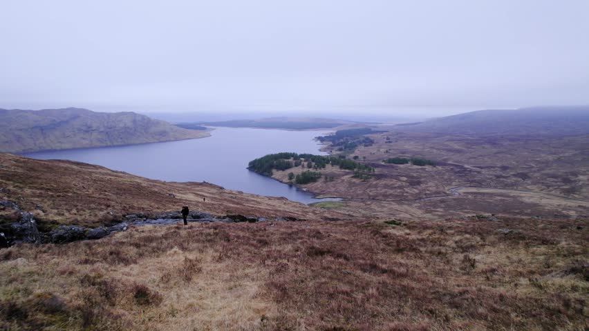 Hiker on a hill next to a river in a swamp of Scotland