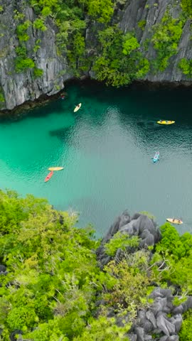 Kayaks running over the Big Lagoon in Miniloc Island. El Nido, Palawan. Philippines. Vertical view.