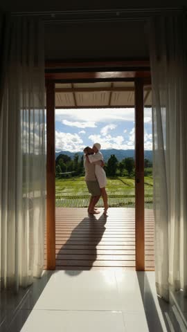 Romantic Couple On Terrace With Mountain And Rice Field View, Woman Embraces And Kisses Her Partner, He Lifts Her Up In A Beautiful Moment Of Love In Scenic Northern Thailand
