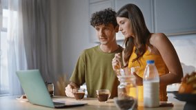 Breakfast lovers looking laptop screen in modern kitchen closeup. Smiling couple watching online show at computer enjoying morning. Cute husband wife tasting granola and coffee laughing in cuisine - Powered by Shutterstock - Get 15% off with code: PIKWIZARD15