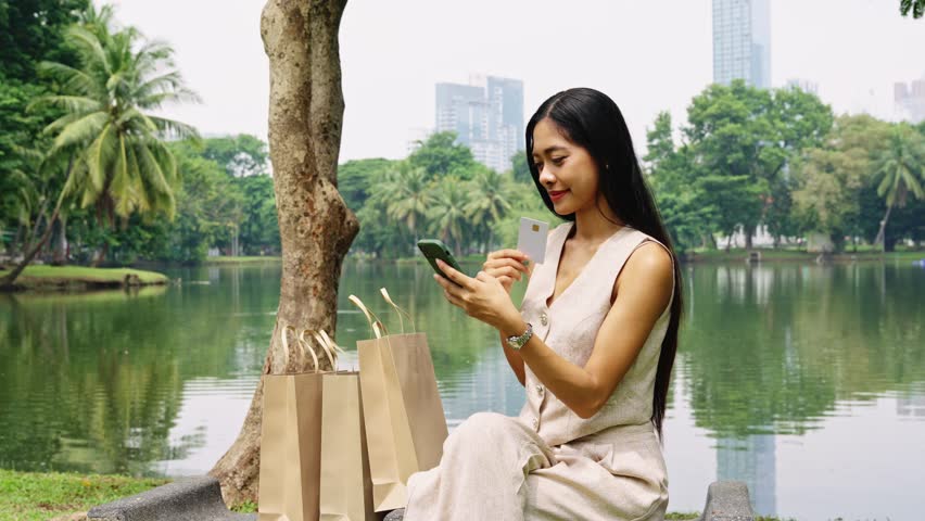 Young woman using credit card shopping online in bangkok park