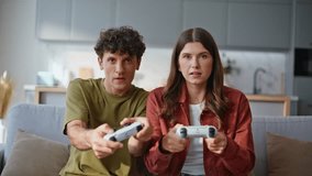 Spouses playing video game at light apartment closeup. Woman winning online competition. Emotional girl holding wireless console feeling happy. Sad boyfriend making disappointed face at living room - Powered by Shutterstock - Get 15% off with code: PIKWIZARD15