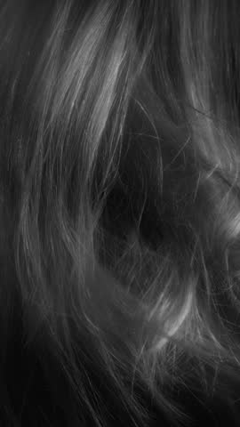 Beauty and glamour hair blowing in the wind in slow motion. Healthy shiny hairs. Hair restoration or care and barbershop or hairdressing concept. Glowing hair macro vertical background