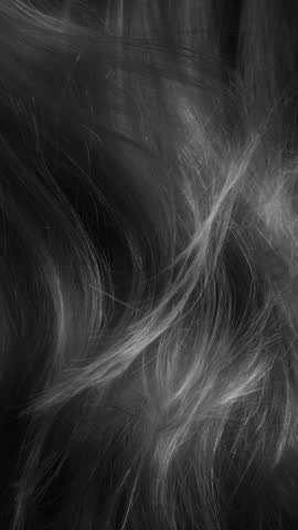 Beauty and glamour hair blowing in the wind in slow motion. Healthy shiny hairs. Hair restoration or care and barbershop or hairdressing concept. Glowing hair macro vertical background