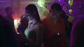 Young people involved phones in neon light nightclub feeling loneliness closeup. Sad couple Illuminated by smartphone glow absorbed in digital interaction at club. Two clubbers ignoring each other. - Powered by Shutterstock - Get 15% off with code: PIKWIZARD15