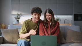 Overjoyed spouses making video conference talking laptop emotionally. Relaxed couple sitting couch having fun at weekend. Joyful laughing pair telling stories to friends spending time at video call  - Powered by Shutterstock - Get 15% off with code: PIKWIZARD15