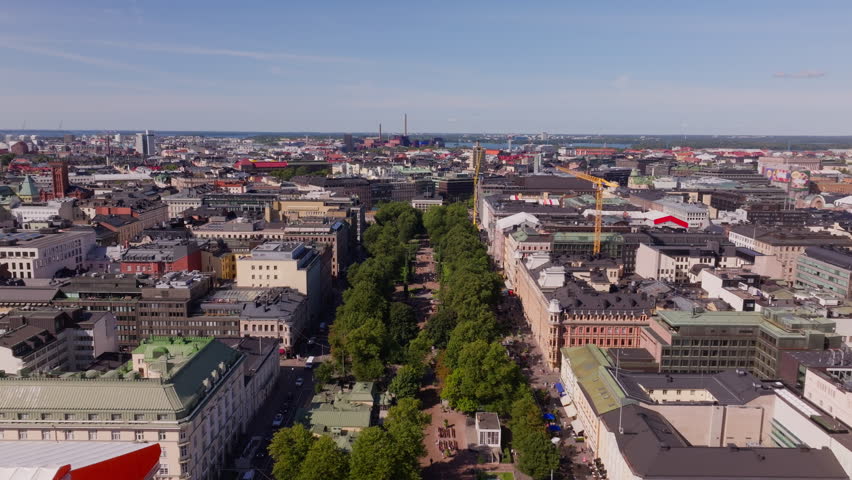 Aerial views highlight Helsinki city center, showcasing the beautiful esplanadi park and impressive architecture. The scene captures a lively urban landscape beneath a clear blue sky