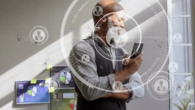 Animation of profile icon in circles over african american man scrolling on smartphone in office. Digital composite, multiple exposure, business, shape, abstract and technology concept. - Powered by Shutterstock - Get 15% off with code: PIKWIZARD15