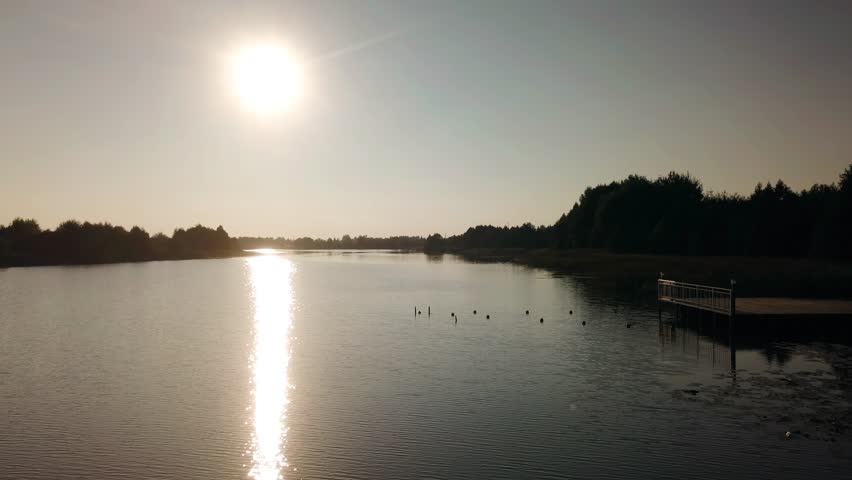 The evening sun shines over the lake and its rays are reflected in the water. Shooting nature from a quadcopter