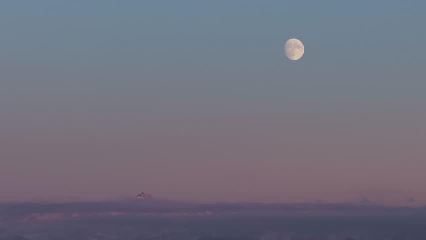Autumn landscape with mountains in the background and fresh snow on the mountain range. Full moon on the mountain peak with sunset. The top of the mountain rises out of the fog.