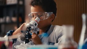 African American boy in lab coat examining sample under microscope, research - Powered by Shutterstock - Get 15% off with code: PIKWIZARD15