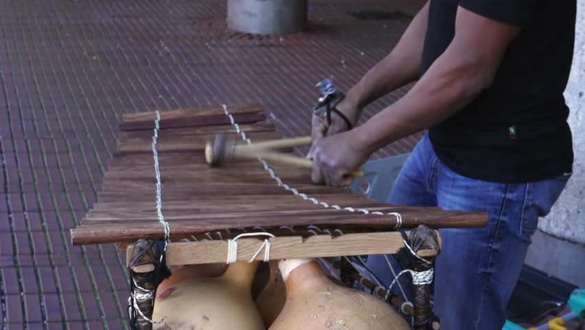 Xylophone play in slow motion, percussion instrument concept - street performer play on wooden bars with mallets in hands