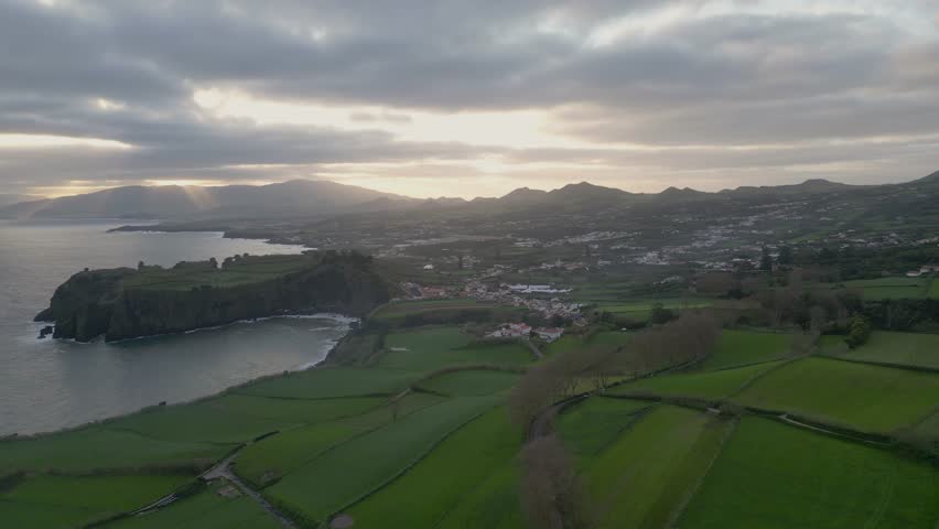 Panoramic aerial view of a bay surrounded by green countryside and village.