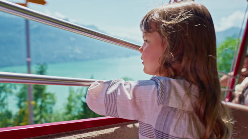 Little girl ride in the famous red rotary steam train leaving the town of Brienz in the Swiss Alps along the alpine meadows to the top of a mountain in summer. Switzerland