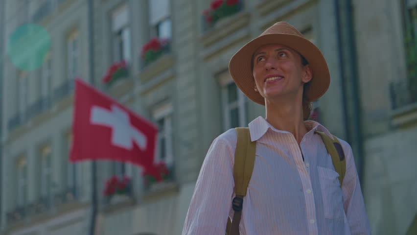An attractive girl in a fashionable hat spends her holidays alone, traveling through the Alpine meadows. Tourist with a backpack travels through Switzerland with incredible views