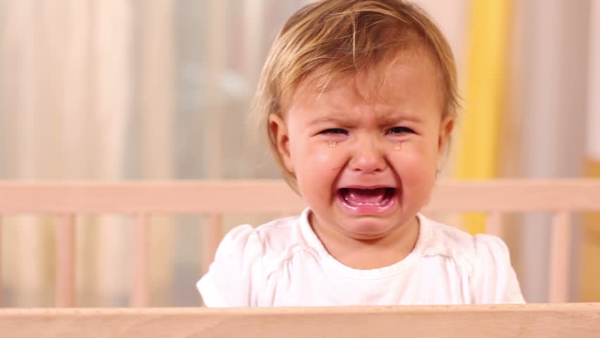 Small girl crying and standing in her bed