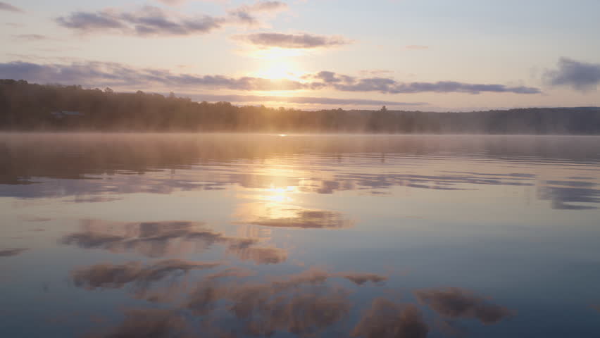 Tranquil sunrise over the lake with fog and cloud reflections