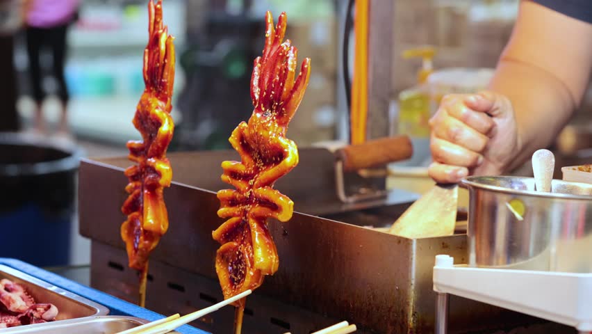 Vendor prepares grilled squid skewers in Hong Kong