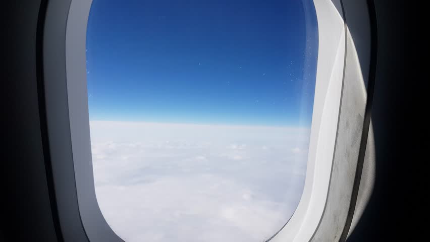 The hand opens and closes the plane window to look out during air travel. Close-up of the window of a flying plane. Airplane over the clouds, 4k video.