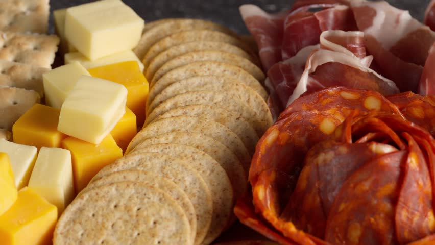 Appetizers boards, macro view of a cheese board, serrano ham, pepperoni rose, green grapes, jam, camera movement from left to right