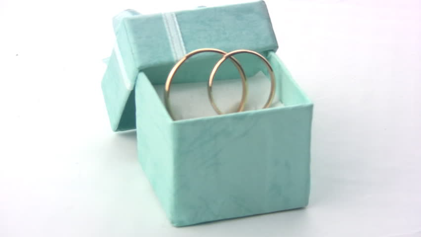 Two wedding rings rotate in the green box with a bow