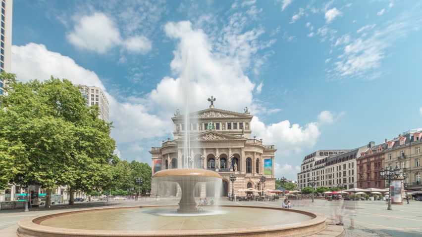 Hyperlapse of the Alte Oper (Old Opera) house in Frankfurt, a concert hall in Opernplatz. The square features a central fountain with people walking around, highlighting historic landmark timelapse
